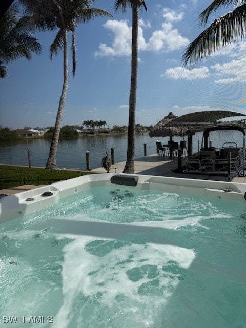 view of swimming pool featuring a dock, a water view, and a hot tub