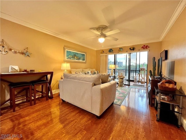 living area featuring a ceiling fan, crown molding, baseboards, and wood finished floors