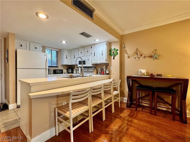 kitchen featuring ornamental molding, white appliances, visible vents, and a peninsula