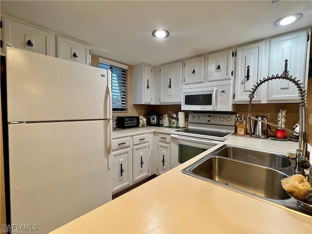 kitchen featuring recessed lighting, white appliances, a sink, white cabinets, and light countertops