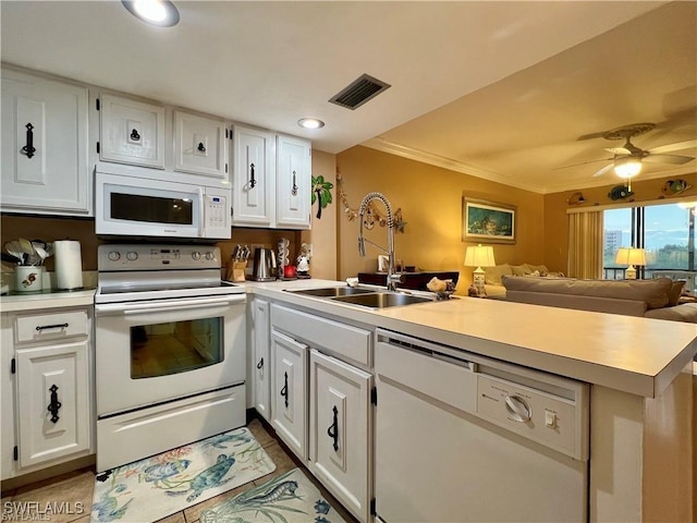 kitchen featuring white appliances, visible vents, a peninsula, light countertops, and a sink