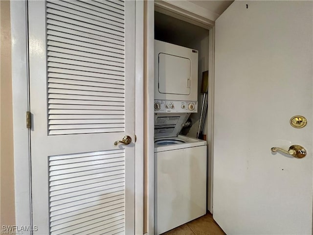 laundry room with tile patterned flooring, stacked washer and clothes dryer, and laundry area