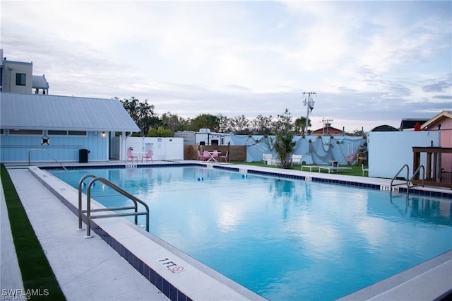 pool featuring an outbuilding, a patio, and fence