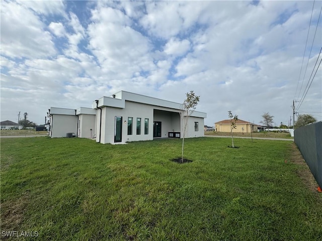 back of house featuring a yard, fence, and stucco siding