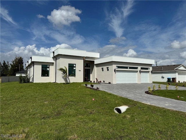 view of front of house featuring a garage, decorative driveway, a front yard, and stucco siding