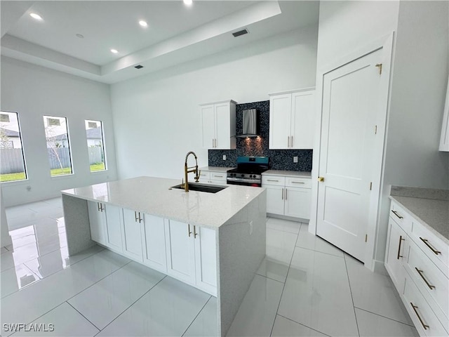 kitchen with visible vents, a tray ceiling, stainless steel electric stove, wall chimney range hood, and a sink