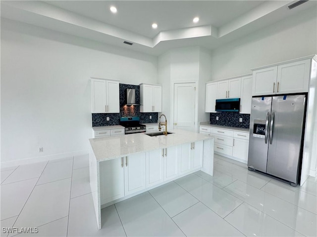 kitchen featuring wall chimney exhaust hood, appliances with stainless steel finishes, a sink, and white cabinetry