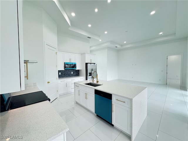 kitchen featuring a kitchen island with sink, a sink, white cabinetry, appliances with stainless steel finishes, and backsplash