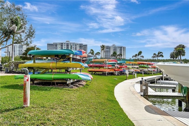 surrounding community featuring a boat dock, boat lift, a view of city, and a yard