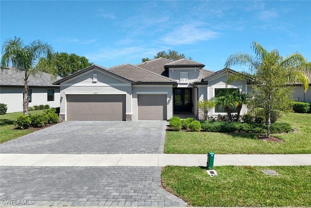 view of front of property featuring a front lawn, a tiled roof, stucco siding, decorative driveway, and an attached garage