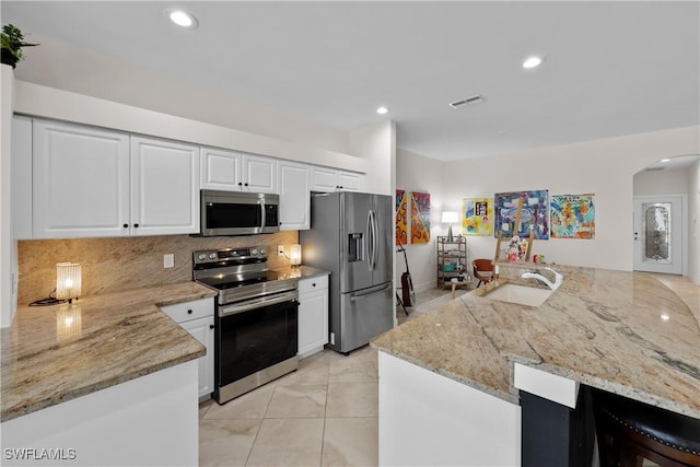 kitchen featuring visible vents, arched walkways, appliances with stainless steel finishes, a sink, and backsplash