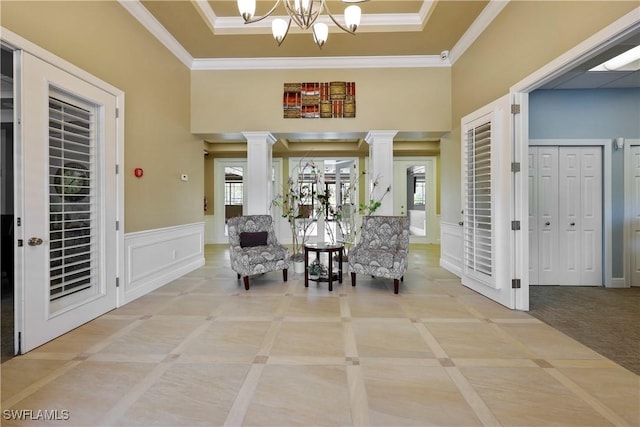 sitting room featuring ornate columns, ornamental molding, a decorative wall, and a wainscoted wall