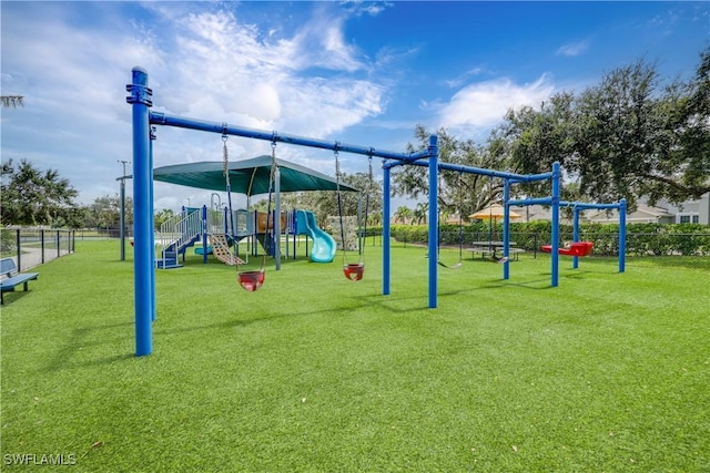 community jungle gym featuring fence and a lawn