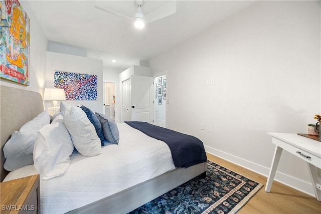 bedroom featuring a closet, wood finished floors, a ceiling fan, and baseboards