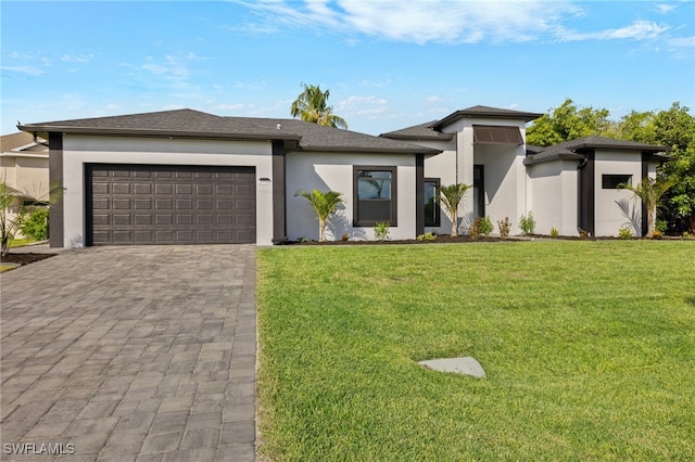 prairie-style house featuring decorative driveway, a front yard, an attached garage, and stucco siding