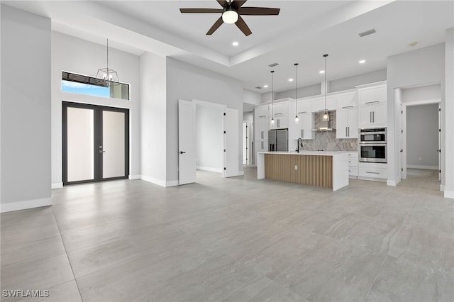 unfurnished living room with visible vents, recessed lighting, a high ceiling, and baseboards