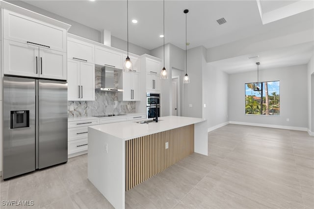 kitchen featuring visible vents, a kitchen island with sink, stainless steel appliances, wall chimney exhaust hood, and backsplash