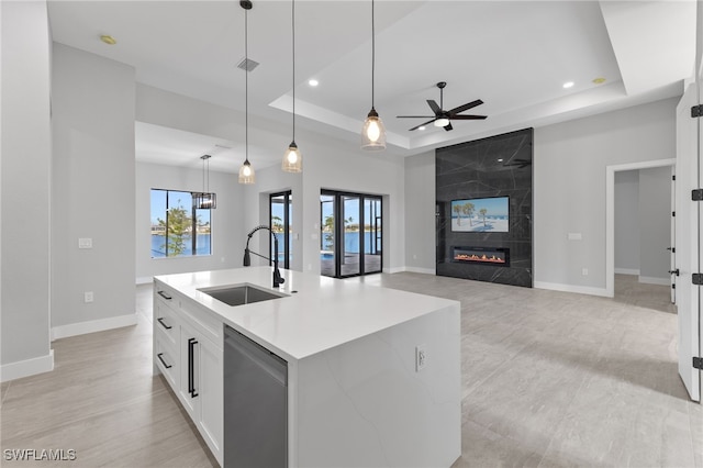 kitchen featuring a sink, a raised ceiling, dishwasher, and a high end fireplace