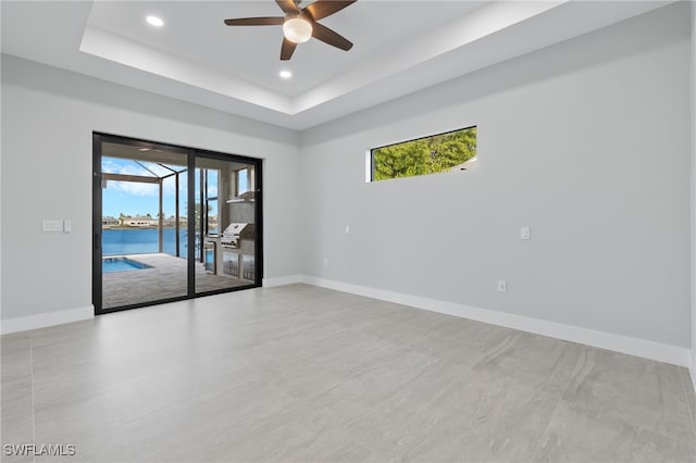 spare room featuring recessed lighting, baseboards, a raised ceiling, and ceiling fan