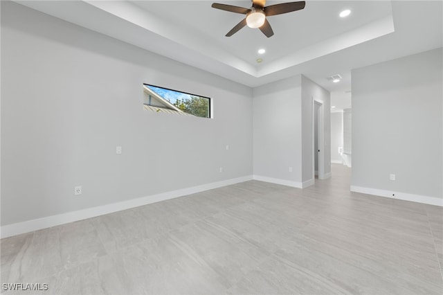 empty room featuring a ceiling fan, a raised ceiling, recessed lighting, and baseboards