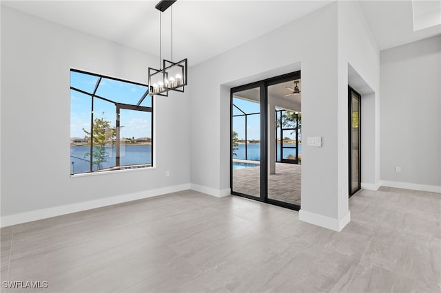 empty room featuring baseboards, ceiling fan with notable chandelier, a water view, and a sunroom