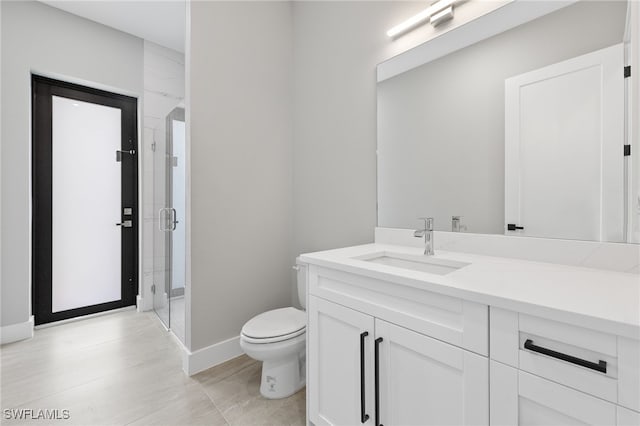 bathroom featuring a stall shower, toilet, vanity, and baseboards