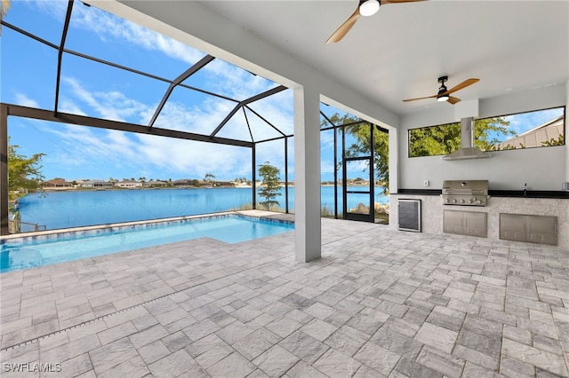 pool with a water view, grilling area, glass enclosure, exterior kitchen, and a patio area