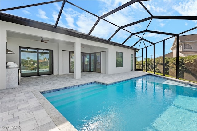 outdoor pool featuring glass enclosure, a patio, exterior kitchen, and a ceiling fan