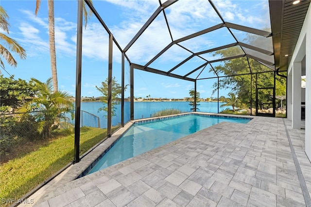 pool featuring glass enclosure, a patio, and a water view