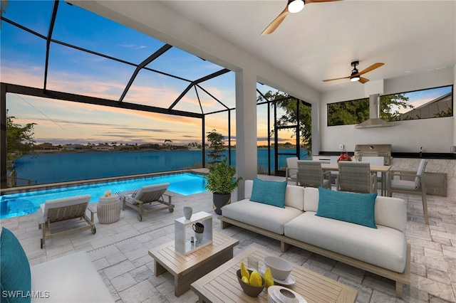 view of patio / terrace with a water view, glass enclosure, an outdoor pool, an outdoor hangout area, and an outdoor kitchen