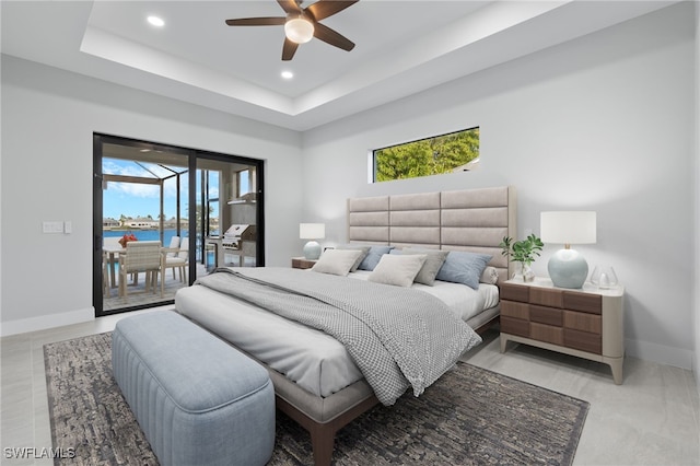 bedroom featuring a raised ceiling, access to outside, multiple windows, and baseboards