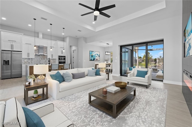 living room with visible vents, a ceiling fan, a tray ceiling, recessed lighting, and baseboards