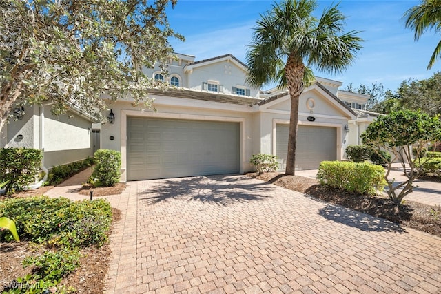 view of front of house featuring decorative driveway, an attached garage, and stucco siding