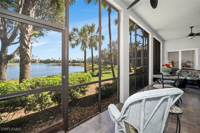 sunroom / solarium featuring ceiling fan and a water view