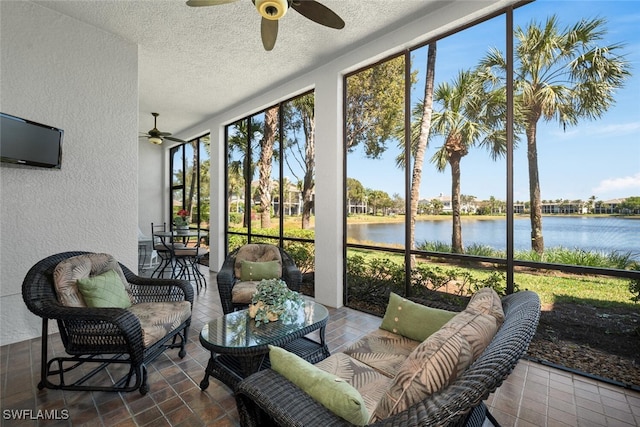 sunroom / solarium featuring a ceiling fan and a water view