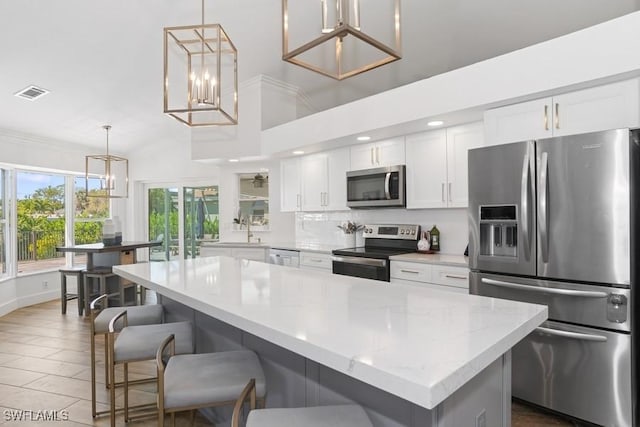 5311 Harborage Dr, Fort Myers, FL 33908 - kitchen with stainless steel appliances, white cabinetry, a breakfast bar, hanging light fixtures, and a chandelier