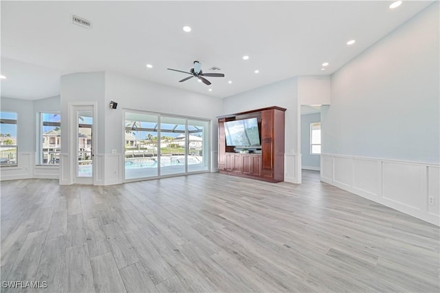 unfurnished living room featuring light wood finished floors, wainscoting, recessed lighting, and a decorative wall