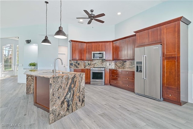 kitchen with backsplash, decorative light fixtures, light stone countertops, stainless steel appliances, and a sink