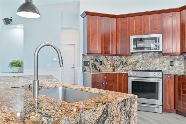 kitchen with dark stone counters, appliances with stainless steel finishes, a sink, and decorative backsplash