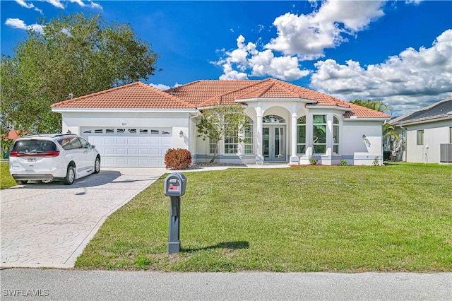 mediterranean / spanish-style house featuring a front yard, french doors, a tiled roof, and an attached garage