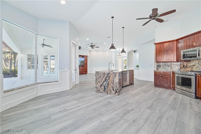 kitchen with a wainscoted wall, stainless steel appliances, lofted ceiling, backsplash, and open floor plan