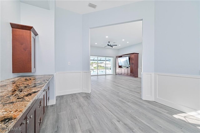 interior space with a wainscoted wall, light wood-type flooring, and visible vents