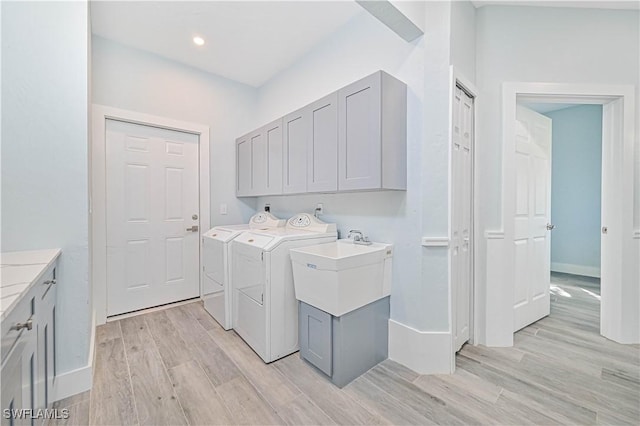 clothes washing area with cabinet space, baseboards, light wood-style floors, washing machine and dryer, and recessed lighting