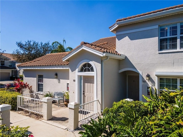 exterior space with stucco siding and a tile roof