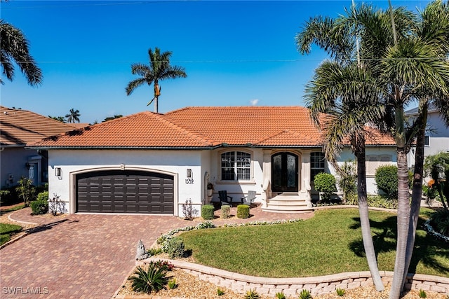 mediterranean / spanish home featuring a front yard, stucco siding, a garage, a tile roof, and decorative driveway