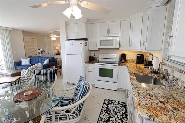 kitchen with white appliances, light tile patterned floors, white cabinets, and a sink