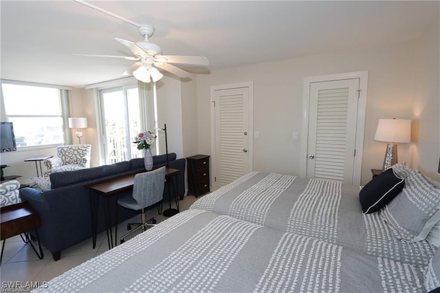 bedroom with light tile patterned floors, ceiling fan, and two closets