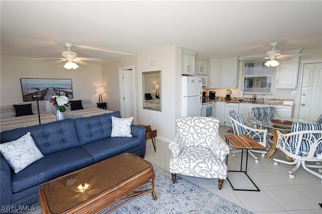 living area with ceiling fan, baseboards, and light tile patterned floors