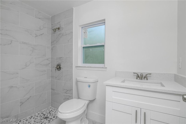 full bathroom featuring tiled shower, vanity, and toilet