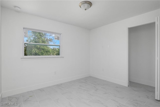 empty room featuring marble finish floor and baseboards